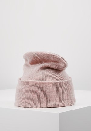 Bonnet en tricot rose doux avec bord replié présenté sur une surface blanche avec un fond clair uni.