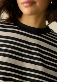 Camiseta a rayas con rayas horizontales en negro y blanco roto, material de algodón, cuello redondo y textura suave.
