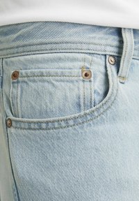 Lys blå denim jeans med slim fit, som har kobbernit, en frontlomme og et teksturert, falmet stoff med synlige sømmer.