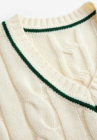 Sweter dzianinowy w kremowym kolorze z zielonymi dodatkami. Posiada wzór w warkocze i dekolt w kształcie litery V. Miękka tekstura, ściągacz przy kołnierzu i akcenty.