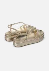 Sandales plateforme dorées avec des brides texturées et scintillantes, un semelle métallique lisse et une semelle rembourrée. Design léger avec des brides croisées.