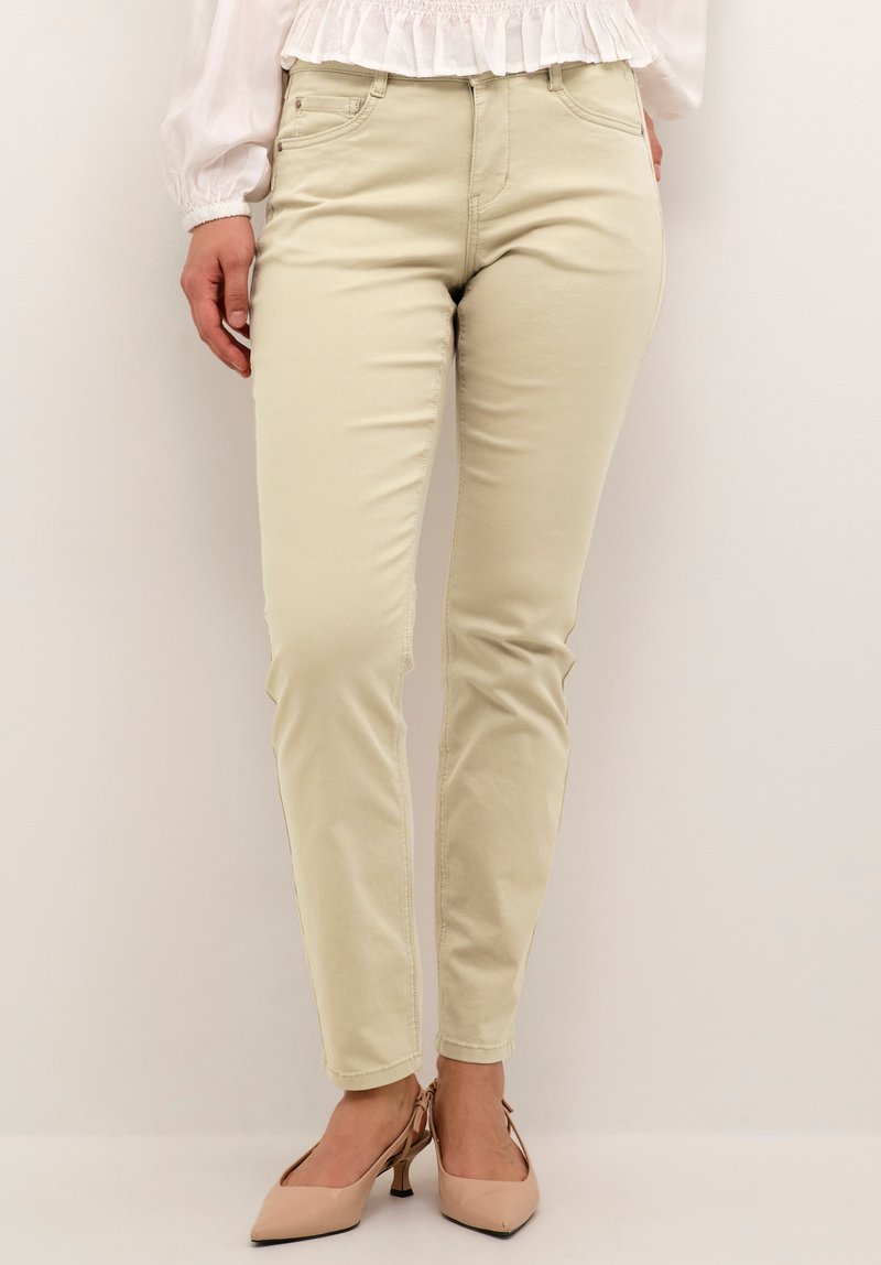 Beige, slimfit jeans med en glat tekstur og let stretch. Har forlommer og bæltestropper. Bruges med nudefarvede spidse hæle.