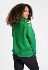 Groene lange mouw top met een hoge kraag, met witte chevron accenten op de schouders en een glad, textuurstof.