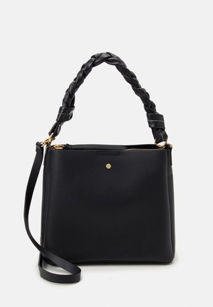 Svart läderhandväska med flätat handtag, guldhardware och dragkedjestängning. Har en hexagonal accent framtill.