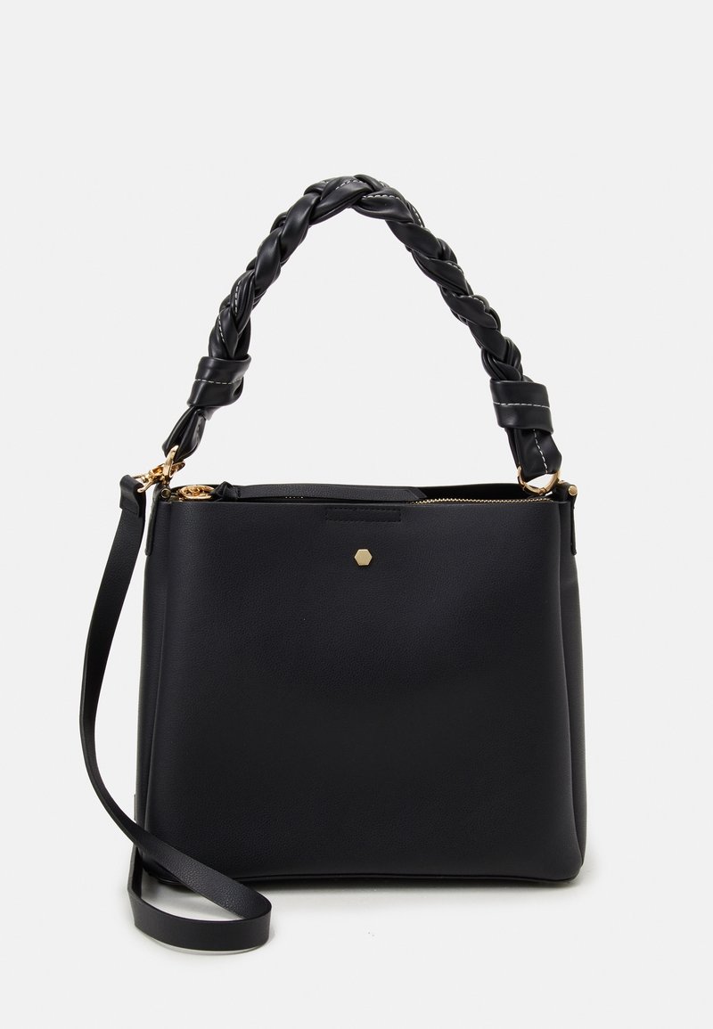 Mustassa nahkaisessa käsilaukussa on punottu kahva, kultaiset yksityiskohdat ja vetoketjukiinnitys. Etupuolella on kuusikulmainen koroste.