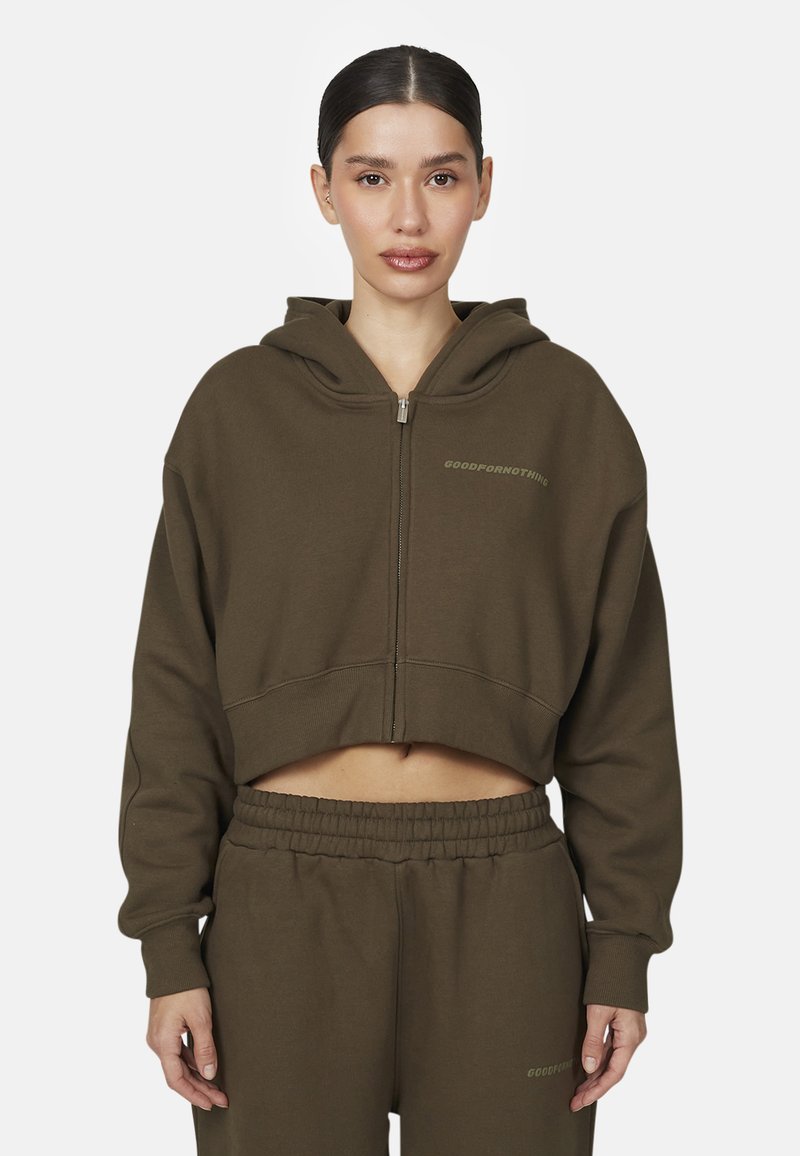 Felpa verde oliva tagliata, con cappuccio e zip frontale, caratterizzata da polsini a costina e la scritta "GOODFORNOTHING" in un font sottile.