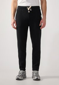 Schwarze Sweatpants aus strukturiertem Stoff, ausgestattet mit einem Kordelzugbund mit cremefarbenem Stopper, slim Fit und knöchellanger Passform.