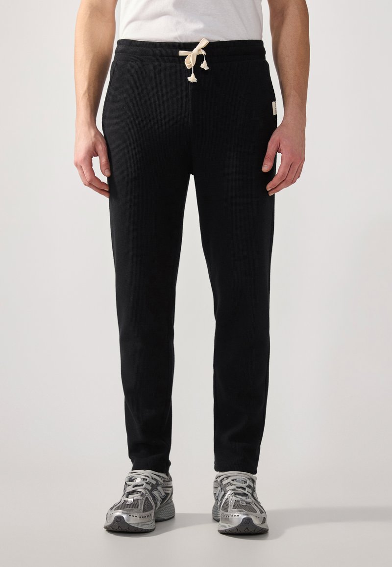Schwarze Sweatpants aus strukturiertem Stoff, ausgestattet mit einem Kordelzugbund mit cremefarbenem Stopper, slim Fit und knöchellanger Passform.