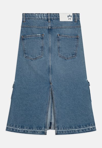 Jupe en jean avec une fente à l'arrière, quatre poches et une étiquette blanche présentant un graphique noir. Elle a un délavage bleu clair et un design mi-long.