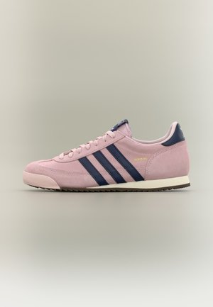 Różowy zamszowy sneaker Adidas z granatowymi paskami, białą podeszwą i złotym logo Adidas po boku.