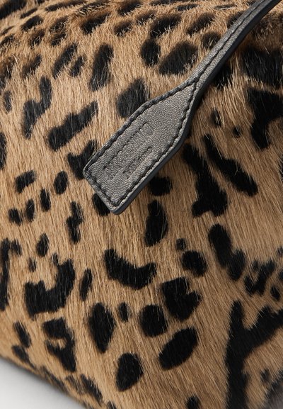 Zbliżenie na miękką tkaninę w kolorze tanowym i czarnym w wzór lamparta, z teksturowanym paskiem ze czarnej skóry z wytłoczonym logo.