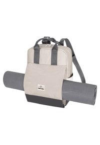 Beige hátizsák szürke pántokkal és részletekkel, nagy elülső zsebbel, amelyben egy feltekert szürke jóga matrac található, tartós anyagból készült.