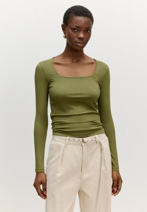 Langarm, ribbed top in olijfgroen met een vierkante halslijn, gecombineerd met crèmekleurige wijde broek met riemlussen en knoopaccenten.
