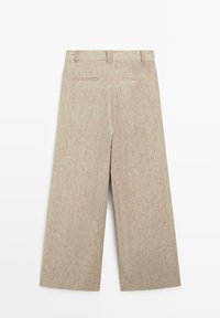 Beige wijde broek met riemlussen en twee achterzakken met bies, gemaakt van gestructureerde stof.