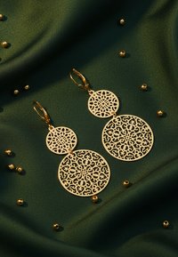 Orecchini dorati con intricati motivi floreali intagliati, caratterizzati da due forme circolari di diverse dimensioni sospese a ganci tipo lever.