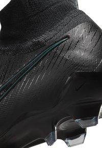 Scarpa da calcio nera con tomaia testurizzata, colletto a calza integrato, striscia di accentazione verde e tacchetti trasparenti per una migliore aderenza sul prato.