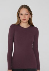 Dopasowana, długosleeve, bluzka w głębokim purpurowym kolorze, wykonana z gładkiego materiału, z okrągłym dekoltem, bez widocznych ozdób czy wzorów.