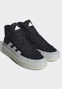 Čierne vysoké tenisky vyrobené z plátna a gumy, so bielou medzizvrškovou podošvou a tromi bielymi pruhmi na boku. Textúrované šnúrky a akcenty.