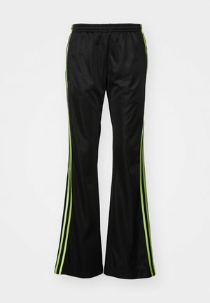 Pantalons de sport noirs à forme évasée, avec des rayures latérales vertes, une taille élastique et une texture de tissu lisse et brillante.