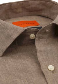 Bruine linnen blouse met een klassieke kraag, twee knopen aan de voorkant en een zichtbaar merkje op een contrasterende oranje achtergrond.