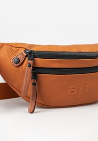 Marsupio in tessuto arancione con una cerniera nera, dettagli in pelle, logo impresso e tracolla regolabile; presenta due scomparti con cerniera.