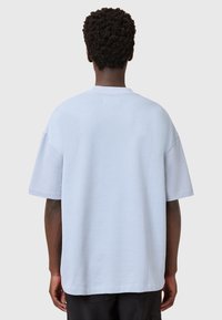 Lichtblauw oversized t-shirt met korte mouwen, ronde hals en een gladde textuur. Kenmerkt zich door minimale stiksels en een relaxte pasvorm.