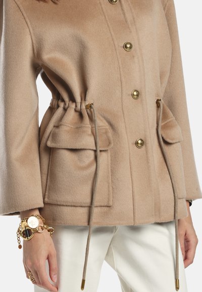 Palton bej din amestec de lână, cu talie ajustabilă prin șnur, nasturi aurii cu capse și două buzunare frontale. Finisaj texturat și croială potrivită.