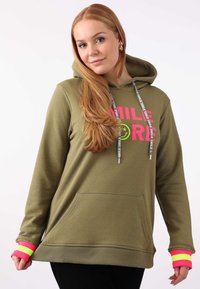 Felpa verde oliva con tasca frontale a forma di canguro, cordini e audace grafica "SMILE MORE" in rosa e giallo. Presenta polsini a strisce colorate.