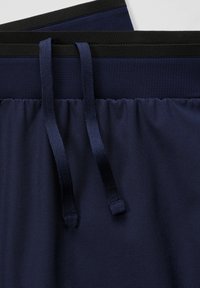 Marineblaue Sportshorts mit einem strukturierten Taillenbund, ausgestattet mit schwarzen Gummibändern und verstellbaren Kordelzügen. Glattes Gewebe mit leichtem Glanz.