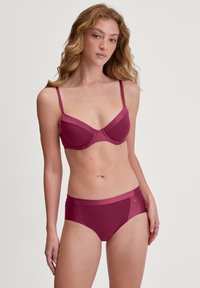 Soutien-gorge de maternité et culottes assorties en bordeaux. Tissu lisse, texture douce, bretelles ajustables, et design minimaliste avec des accents subtils.