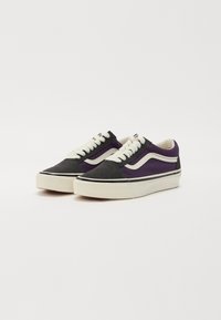 Zapatillas bajas con un upper de ante negro y púrpura, cordones blancos y una gruesa suela de goma crema. Presentan franjas laterales blancas en contraste.