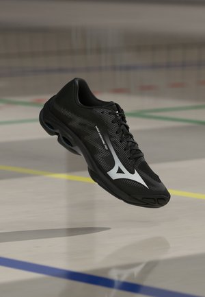 Crna sportska cipela s bijelim logom i tekstom "Wave Lightning Pro" lebdi iznad unutarnjeg poda terena s šarenim linijama.