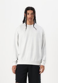 Lys grå sweatshirt med en afslappet pasform, rund halsudskæring og ribbede manchetter. Har et lille logo på venstre bryst og en tekstureret stof.