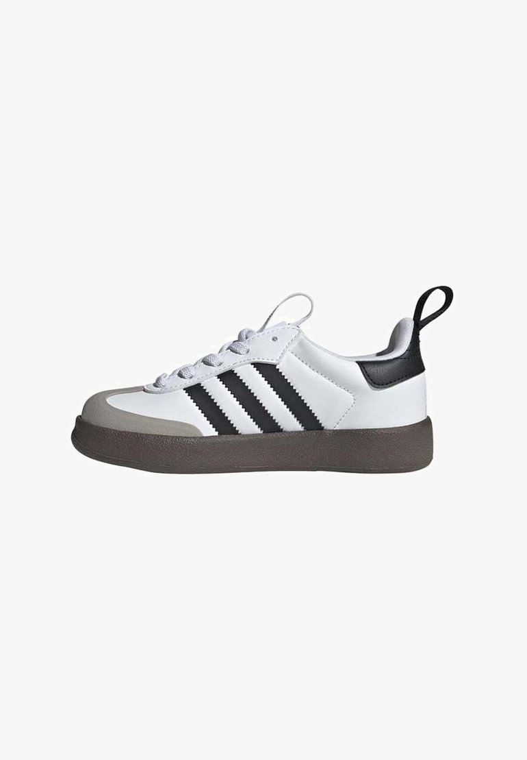 White athletic shoe with black leather accents, three black stripes, grey rubber toe cap, and textured brown sole. Laces in light grey.