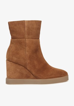 Bruna ankelboots i mocka med kilklack, slät textur, avsmalnande design och rundad tå. Har dold kilklack och utan synliga detaljer.