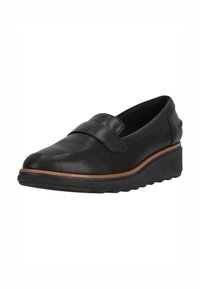 Svart läder slip-on sko med rund tå, texturerad ovandel och en kontrasterande brun gummisula. Har en dekorativ rem över framsidan.