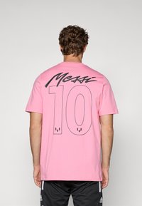 Pink cotton t-shirt featuring a large black "Messi" graphic and the number "10" on the back, crew neck design, relaxed fit.