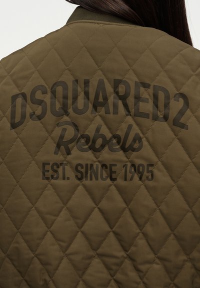 Πράσινο ελιάς καπιτονέ μπουφάν, πίσω μέρος με την επιγραφή "DSQUARED2 Rebels EST. SINCE 1995" σε μαύρα γράμματα σε τρεις γραμμές.