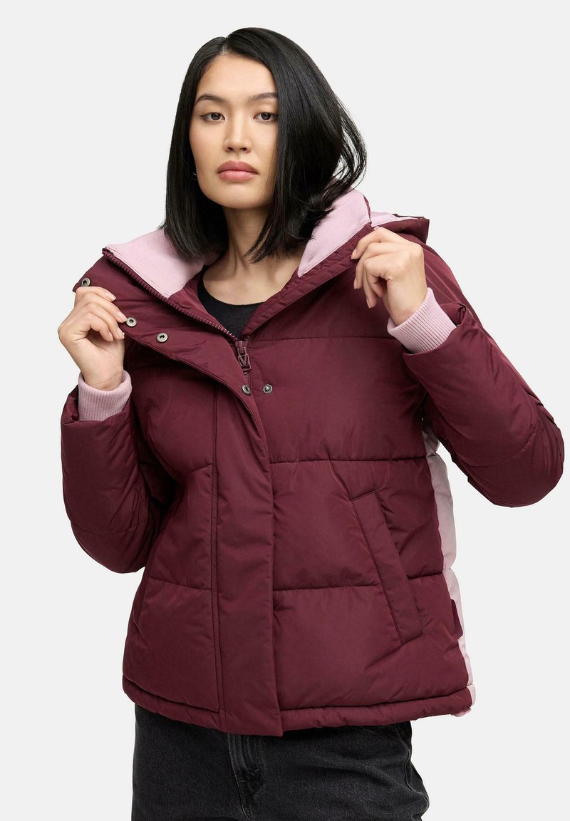 Veste matelassée bordeaux avec une capuche rose, des accents sur les côtés et des poignets côtelés. Dotée d'une fermeture zippée et de poches avant avec une texture matelassée.