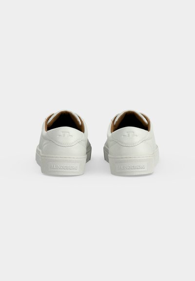 Ζευγάρι λευκά low-top αθλητικά παπούτσια με ανάγλυφο λογότυπο στην φτέρνα και καουτσούκ σόλες, σε θέα από το πίσω μέρος σε απλό φόντο.