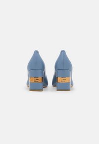 Chaussures en cuir bleu à talons blocs avec bouts pointus. Présentent un accent métallique doré sur le talon et une texture lisse.