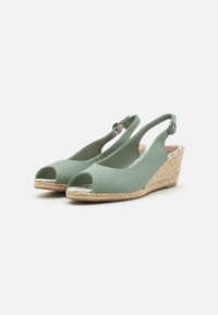 Sandales compensées en tissu vert avec orteils ouverts, design à lanière arrière et semelle en jute tressé. Présente une boucle ronde et une semelle intérieure texturée.