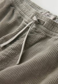 Hellgraue, gerippte Loungehosen mit einem elastischen Bund und verstellbarem Kordelzug. Das Etikett zeigt den Markennamen "NEXT." Weicher Stoff.