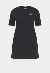Czarna bawełniana sukienka T-shirt z krótkim rękawem, okrągłym dekoltem i małą tkana łatą logo po lewej stronie klatki piersiowej. Gładka tekstura, luźny krój.