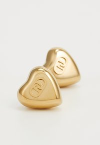 Gold heart-shaped earrings with a smooth surface and embossed logo. Features a polished finish and rounded edges for comfort.