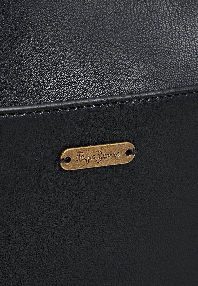 Material de cuero sintético negro con acabado texturizado. Presenta una etiqueta de metal dorado con "Pepe Jeans" grabado. Diseño simple y limpio.