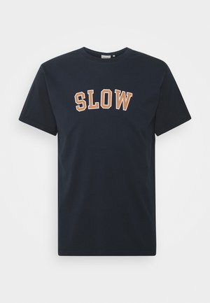 Navy-Baumwoll-T-Shirt mit dem Wort "SLOW" in kräftigen, kontrastierenden orangefarbenen Buchstaben, klassischem Rundhalsausschnitt und kurzen Ärmeln.