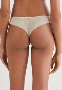 Béžové průhledné bikiny s nízkým pasem a hladkým povrchem, s bezešvým zadním dílem a minimalistickým designem.