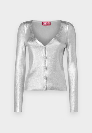 Ezüst, bordázott cardigan hosszú ujjakkal, V-nyakkivágással és gombos záródással. Fényes, texturált anyagból készült. Piros márkajelzés a nyakkivágásnál.
