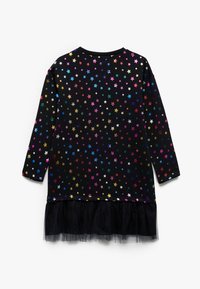 Schwarzes Kleid mit langen Ärmeln, das mit mehrfarbigen Sternmustern und einem Tüll-Rüschensaum versehen ist. Hergestellt aus Baumwolle, mit lässiger Passform.